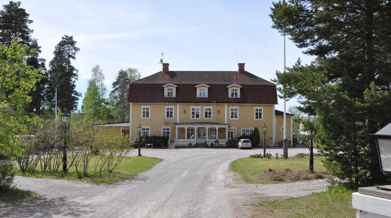 Korstäppan, bild från Hjortnäsvägen. En större två– och enhalvplansbyggnad i trä med fasader av gulmålad liggande spontpanel.