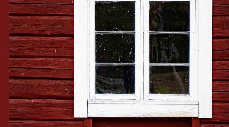 Rödfärgat fähus med blyspröjsat fönster.